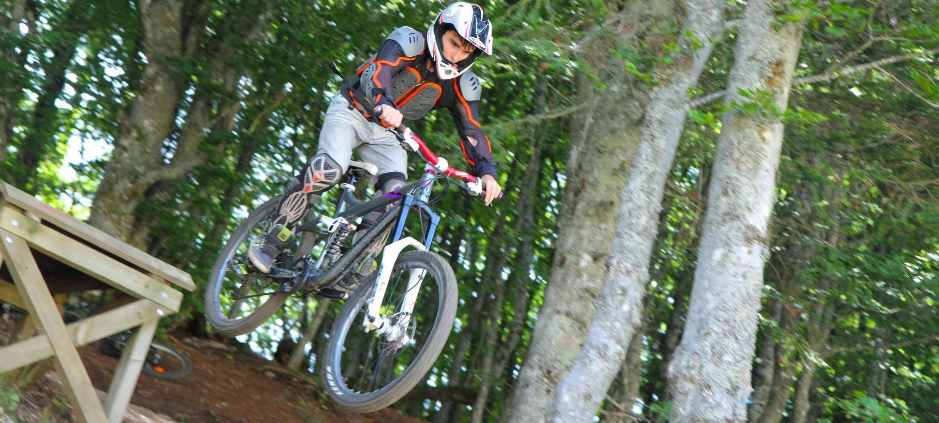 Downhill mountain biking in Super Besse, jumping from a springboard