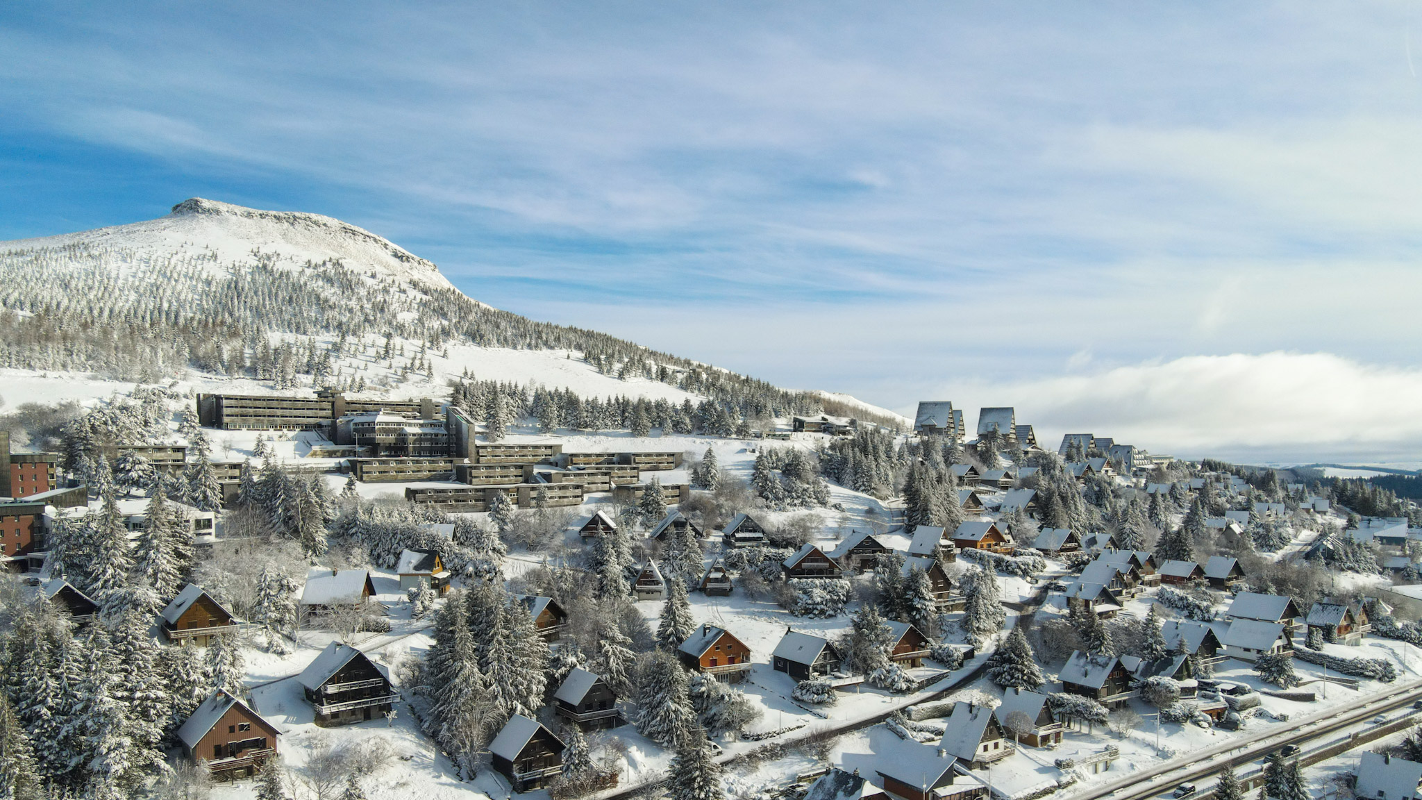 Super Besse seen from the sky under the snow, the slopes of the Puy du Chambourguet and the snow-covered Chalet Village