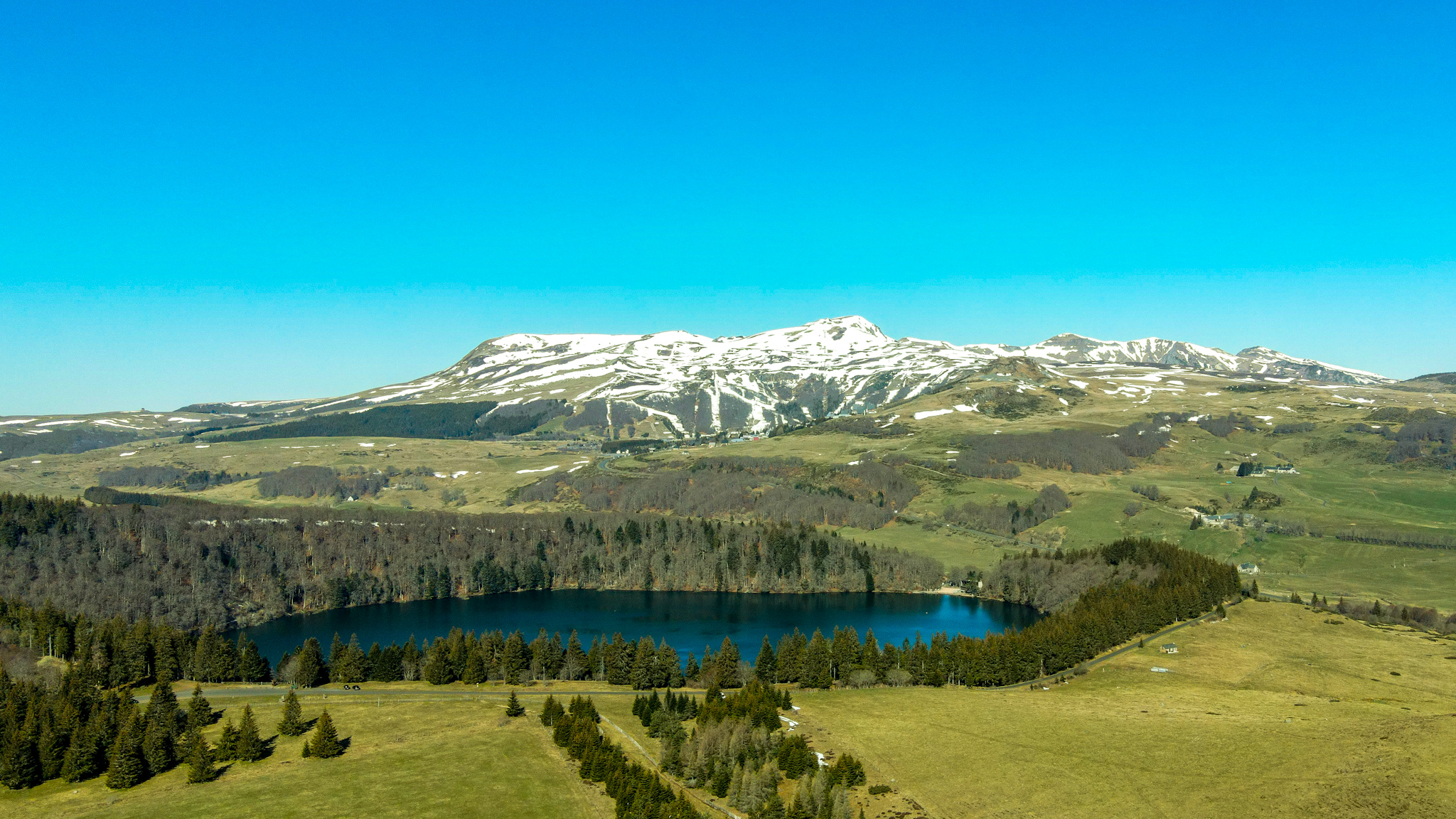 Lake Pavin and the snow-covered resort of Super Besse in Spring